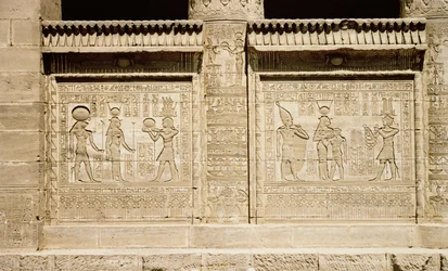 Deux reliefs représentant, à gauche, un pharaon faisant une offrande à Hathor et Horus et, à droite, Hathor allaitant le jeune Ihy avec un deuxième Ihy portant la couronne blanche de la Haute-Égypte derrière lui